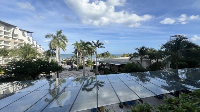 Excellence Playa Mujeres resort grounds with palm trees, reflection pool, and Caribbean Sea